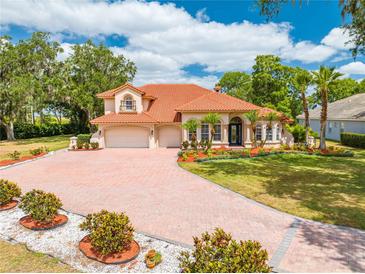 Stunning two-story home featuring a red tile roof, circular drive, lush landscaping, and a three-car garage at 1654 Marina Lake Dr, Kissimmee, FL 34744