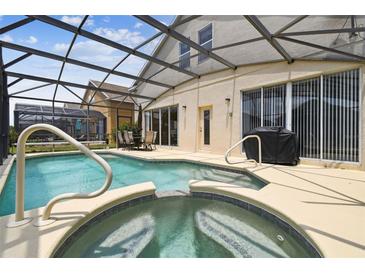 Screened-in pool and spa area featuring a built-in hot tub and relaxing patio furniture at 223 Cadiz Loop, Davenport, FL 33837