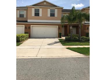 Two-story townhome with a two car garage, a driveway, and lush green landscaping at 3319 Rodrick Cir, Orlando, FL 32824