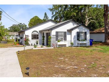Charming white home with a well-maintained lawn, complemented by decorative plants and a welcoming entryway at 106 Edgewater Dr, St Cloud, FL 34769