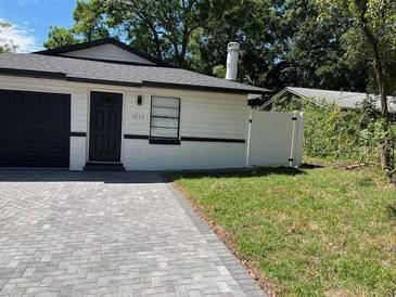 Cozy single-story home featuring a dark garage door and a meticulously paved driveway at 1256 S Bumby Ave, Orlando, FL 32806