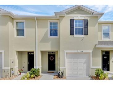 Charming two-story townhome featuring a single-car garage, neat landscaping, and welcoming front entrance at 1219 Lido Dr, Howey In The Hills, FL 34737