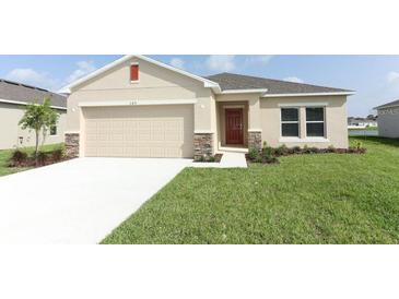 Charming single-story home featuring a neutral color palette, two-car garage, and well-manicured lawn at 165 Citrine Loop, Kissimmee, FL 34758