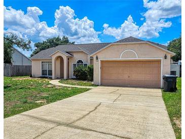 Charming single-story home featuring a well-maintained lawn and attached two-car garage at 215 Grovepark Dr, Davenport, FL 33837