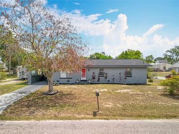 Charming single-story home with grey paint, red front door and well-maintained lawn at 320 S Seminole Ave, Lake Alfred, FL 33850