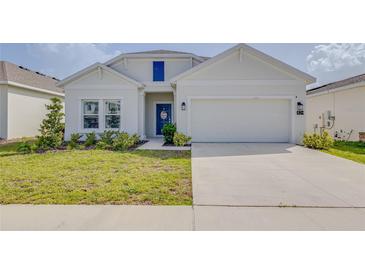 Charming single-Gathering home featuring a well-manicured lawn, blue door, and attached two-car garage at 824 Ofanto Way, Haines City, FL 33844