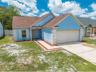Charming one-story blue home with a two-car garage and manicured front yard at 8322 Cascade Oaks Dr, Orlando, FL 32822