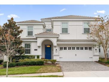 Beautiful two-story white home featuring a blue front door, two-car garage, and manicured landscaping at 9020 Stinger Dr, Davenport, FL 33896