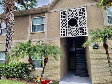 Condo exterior with palm trees, brick accents, a stairwell, and decorative white latticework above the entrance at 9916 Sweepstakes Ln # 7, Orlando, FL 32837