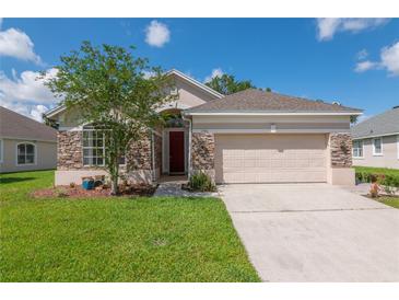 Charming single-story home with a stone facade, well-maintained lawn, and a two-car garage on a sunny day at 1746 Golfview Dr, Kissimmee, FL 34746