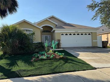 Inviting single-story home with a well-maintained front yard, manicured bushes, and an attached two car garage at 2567 Oneida Loop, Kissimmee, FL 34747