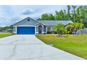 Charming single-story home featuring a well-manicured lawn and a bright blue two-car garage door at 330 Chiquita Ct, Kissimmee, FL 34758