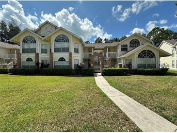 Inviting two-story condo with large windows, landscaped lawn, and charming walkway under a sunny blue sky at 5017 Laguna Bay Cir # 96, Kissimmee, FL 34746