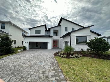 Stunning modern home with a brick driveway, attached garage and beautifully landscaped front yard at 9004 Santorini Dr, Orlando, FL 32827