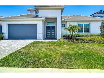 Contemporary home featuring a well-manicured lawn, gray garage door, and a modern entrance with sleek, dark gray doors at 235 Hampton Loop, Davenport, FL 33837