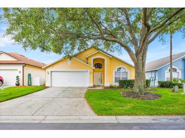 Charming single-Gathering home featuring an attached two-car garage and a well-manicured front lawn with mature tree at 1113 Casterton Cir, Davenport, FL 33897