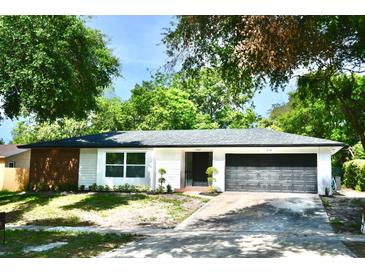 Charming single-story home with a brick accent, dark garage door, and lush landscaping at 2074 Dunsford Dr, Orlando, FL 32808