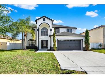 Stunning two-story home featuring a black-trimmed, white exterior, lush lawn, and ample driveway space at 242 Anson Dr, Kissimmee, FL 34758