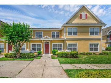 Charming two-story townhome with red door, white picket fence, and lush landscaping at 2614 Lodi Cir # 106, Kissimmee, FL 34746