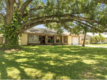 Inviting single-story home featuring a well-manicured lawn and mature shade tree at 42 Chip Ct, Kissimmee, FL 34759