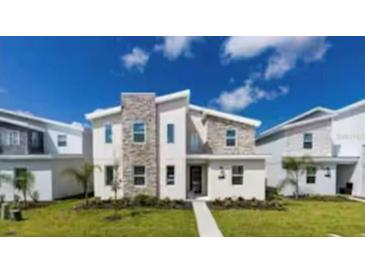 Modern two-story home featuring stone accents, a manicured lawn, and a bright, inviting entrance at 9118 Sommerset Hills Dr, Davenport, FL 33896