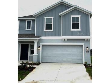 Charming two-story home with a gray exterior, a two-car garage, and a well-maintained front yard at 1053 Waterfall Blvd, Davenport, FL 33837