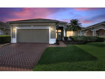 Charming single-story home with brick driveway, lush lawn, and attached two-car garage at 124 Ashton Dr, Davenport, FL 33837