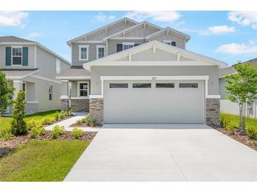Charming two-story home featuring a neutral color palette, stone accents, manicured landscaping, and an inviting front entrance at 227 Bull Frog Ln, Umatilla, FL 32784