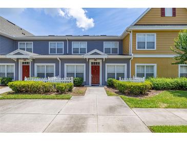 Charming townhome exterior featuring colorful facades, white picket fences, and landscaped greenery under a sunny sky at 2620 Lodi Cir # 103, Kissimmee, FL 34746