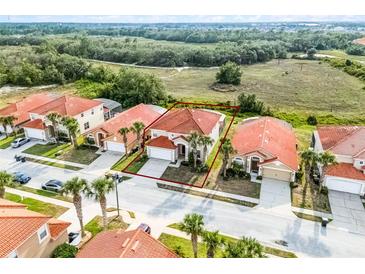 An aerial view showcases a well-maintained home featuring a red tile roof and palm tree landscaping at 321 Rosso Dr, Davenport, FL 33837