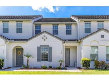 Charming townhome featuring a modern white exterior, landscaped lawn, and stylish gray door at 386 Captiva Dr, Davenport, FL 33896