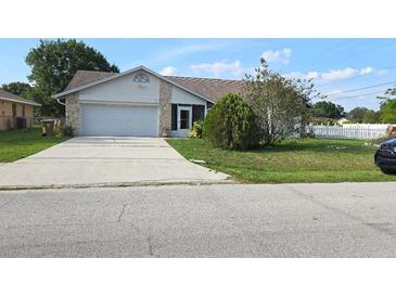 Single story home with a 2-car garage, stone accents, green grass and mature landscaping at 501 Kilimanjaro Dr, Kissimmee, FL 34758