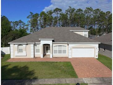 Charming single-story home with a well-manicured lawn and a brick-paved driveway leading to an attached garage at 518 Brighton Dr, Davenport, FL 33897