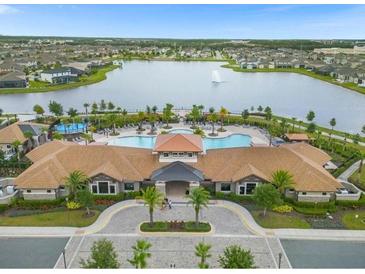 Stunning aerial view of a community pool, clubhouse, and lake surrounded by beautiful homes at 2621 Amati Dr, Kissimmee, FL 34741