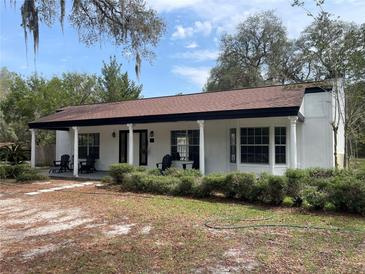 Charming exterior view of a single story home with columns, a front porch, mature landscaping, and a spacious front yard at 8310 Happy Trails, Kissimmee, FL 34747