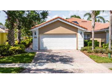 Features a two-car garage, red brick driveway, well-manicured lawn, and beautiful landscaping at 12041 Kajetan Ln, Orlando, FL 32827