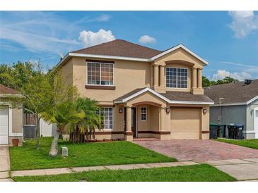 Charming two-story home with a well-manicured lawn, brick driveway, and inviting entrance at 1425 Carey Glen Cir, Orlando, FL 32824
