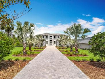 Stunning two-story home featuring a grand entrance, lush landscaping, and a beautiful grey paver driveway at 15121 Pendio Dr, Montverde, FL 34756