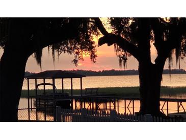 Picturesque waterfront view from the dock with a covered area, complemented by a vibrant sunset at 2740 Barker Rd, St Cloud, FL 34771