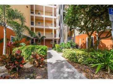 Apartment building featuring multiple stories with balconies, lush landscaping, and a brick walkway at 9055 Treasure Trove Ln # 409, Kissimmee, FL 34747