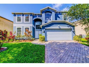 Beautiful two-story home with a well-maintained lawn, landscaped flowerbeds, and a brick driveway at 12715 Moss Park Ridge Dr, Orlando, FL 32832