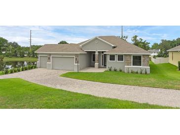 Charming single-story home featuring a three-car garage, well-maintained lawn, and elegant stone accents at 1504 Cordgrass Way, Lakeland, FL 33813