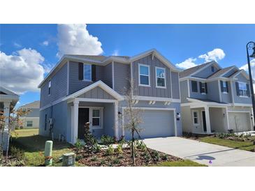 Beautiful new construction home with a well-maintained lawn and a covered front entryway at 443 Cool Summer Ln, Davenport, FL 33837