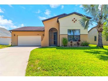 Charming home featuring an arched entry, two-car garage, and a well-manicured front lawn with a palm tree at 4720 Doral Pointe Dr, Kissimmee, FL 34758