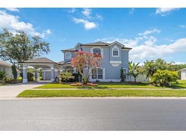 Charming two-story home with a well-manicured lawn, porte-cochere, and classic architectural details at 12134 Shadowbrook Ln, Orlando, FL 32828