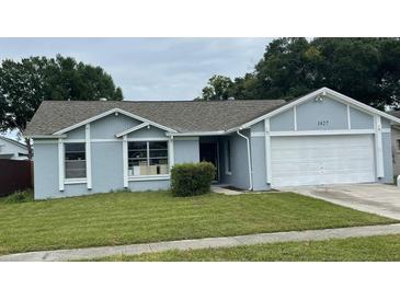 Charming single-story home with a well-maintained lawn, attached garage, and neutral-colored exterior at 1427 Orchid Ln, Kissimmee, FL 34744
