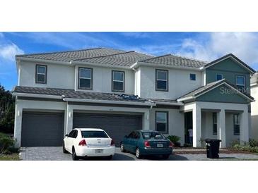 Charming two-story home featuring a three-car garage and inviting front porch with lush landscaping at 4437 Ganesha Loop, Kissimmee, FL 34746
