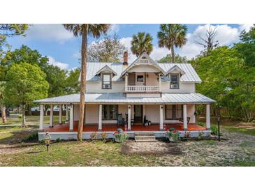 Charming two-story home featuring a large front porch with beautiful architectural details and mature trees at 525 W Blue Springs Ave, Orange City, FL 32763