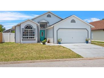 Charming single-Gathering home features a teal front door, well-maintained lawn, and an attached two-car garage at 142 Ethan Ave, Davenport, FL 33897