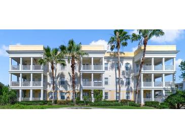 Three-story condo building with balconies and palm trees at 1501 Northern Harrier Way # 202, Reunion, FL 34747